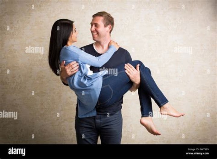 He is carrying both his babies and standing in front of a huge Christmas tree.